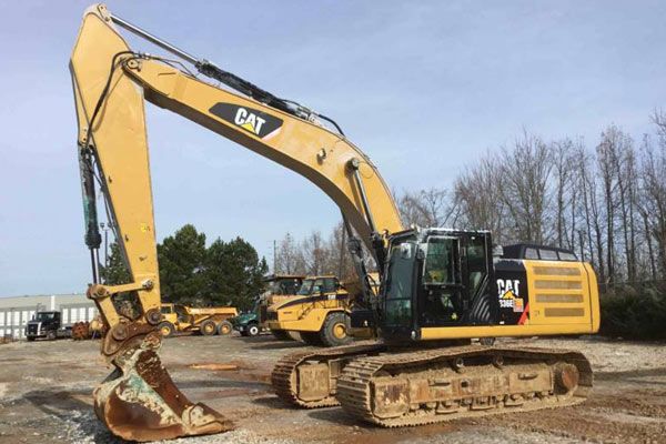 En gul Caterpillar grävmaskin parkerad på en maskindepå inför byggauktion.